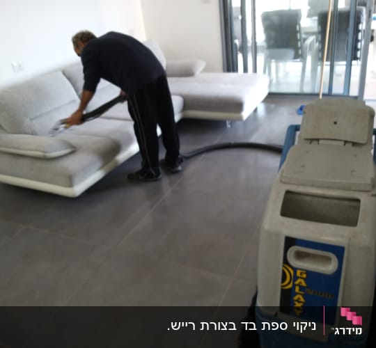 אדם מנקה ספה עם שואב אבק מקצועי